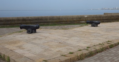 石畳に模型の大砲が2門、海に向った写真。