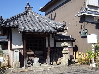 四角の辻堂風の祠。瓦屋根。右側に説明板。